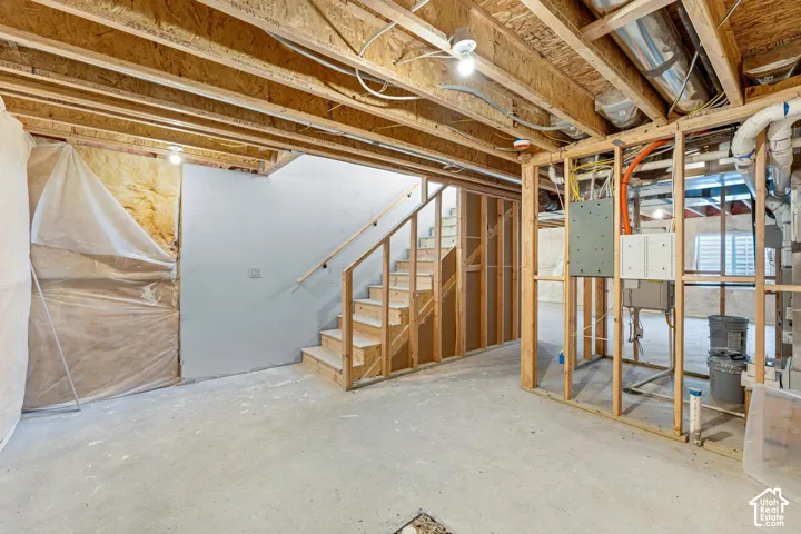 Unfinished basement with exposed ceiling joists, concrete flooring, and partial wall framing