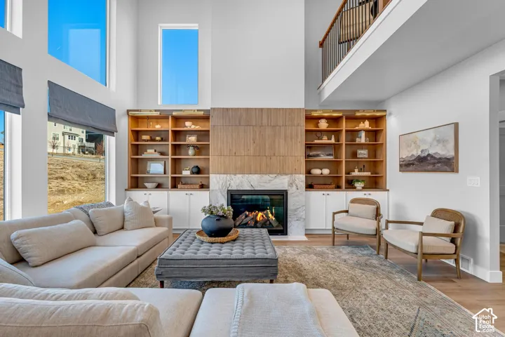 Two-story living area with tall windows, a built-in fireplace, and integrated shelving with lower cabinetry