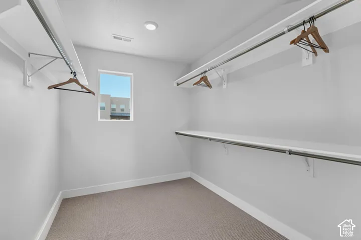 Walk-in closet featuring built-in shelving, hanging rods, recessed lighting, and a window