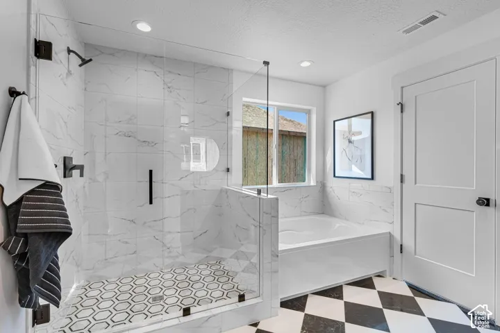 Glass-enclosed shower with honeycomb tile flooring and dark bronze fixtures