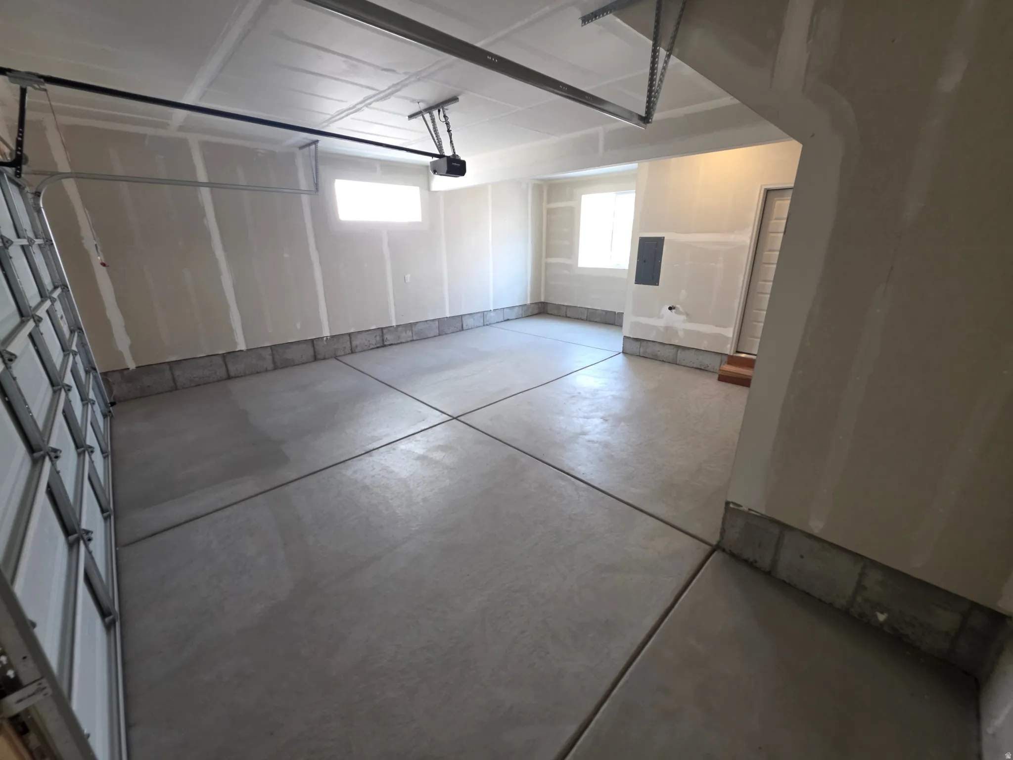 Spacious garage featuring concrete flooring with expansion joints, overhead door with translucent panels, and abundant natural light from multiple windows