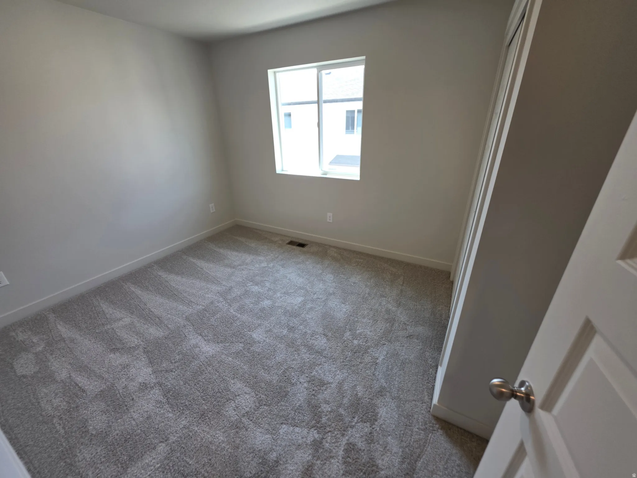 Neutral wall color, carpeted flooring, window with natural light, white trim, and a white interior door