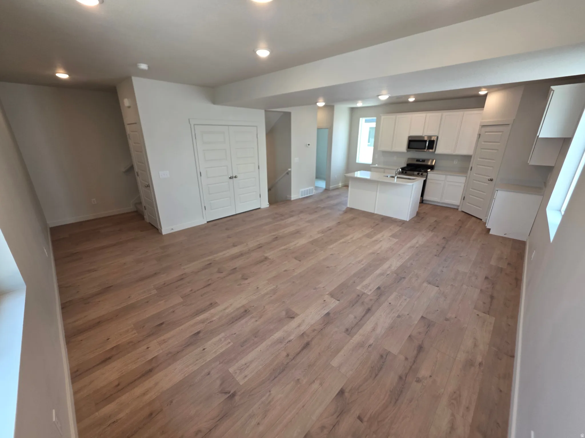 Open-concept living space with wood-finish flooring, recessed lighting, and white bi-fold doors