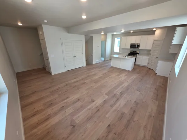 Open-concept living space with wood-finish flooring, recessed lighting, and white bi-fold doors
