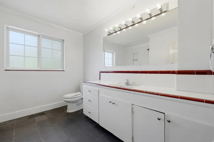 White vanity with extensive storage, integrated sink, and white countertop