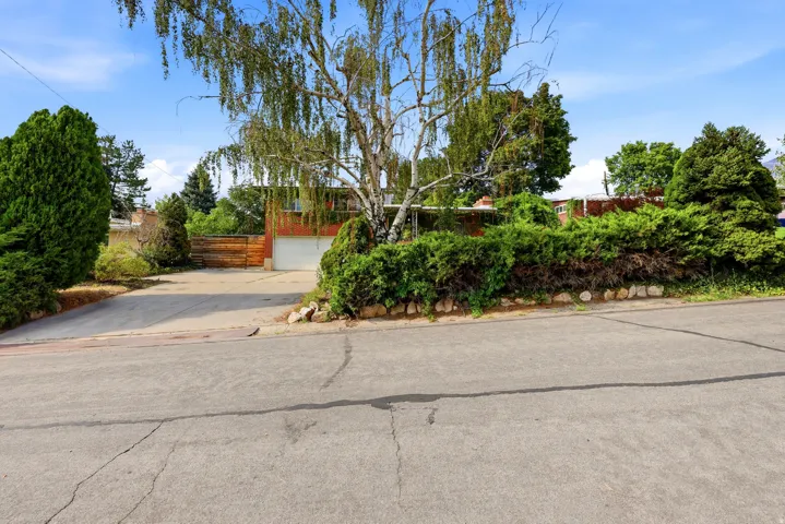 Mature landscaping, paved driveway, attached garage, brick-finish exterior