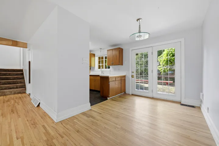 Bright and open kitchen and dining area featuring wood cabinetry, stainless steel appliances, and wood-finish flooring throughout