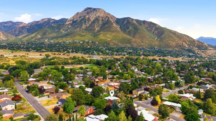 Mountain backdrop framing a residential area with mature trees and a clear sky