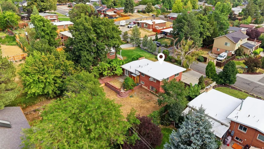 Brick exterior residence with a white roof, surrounded by mature trees