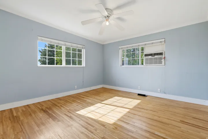 Hardwood flooring with natural light, ceiling fan, and two windows
