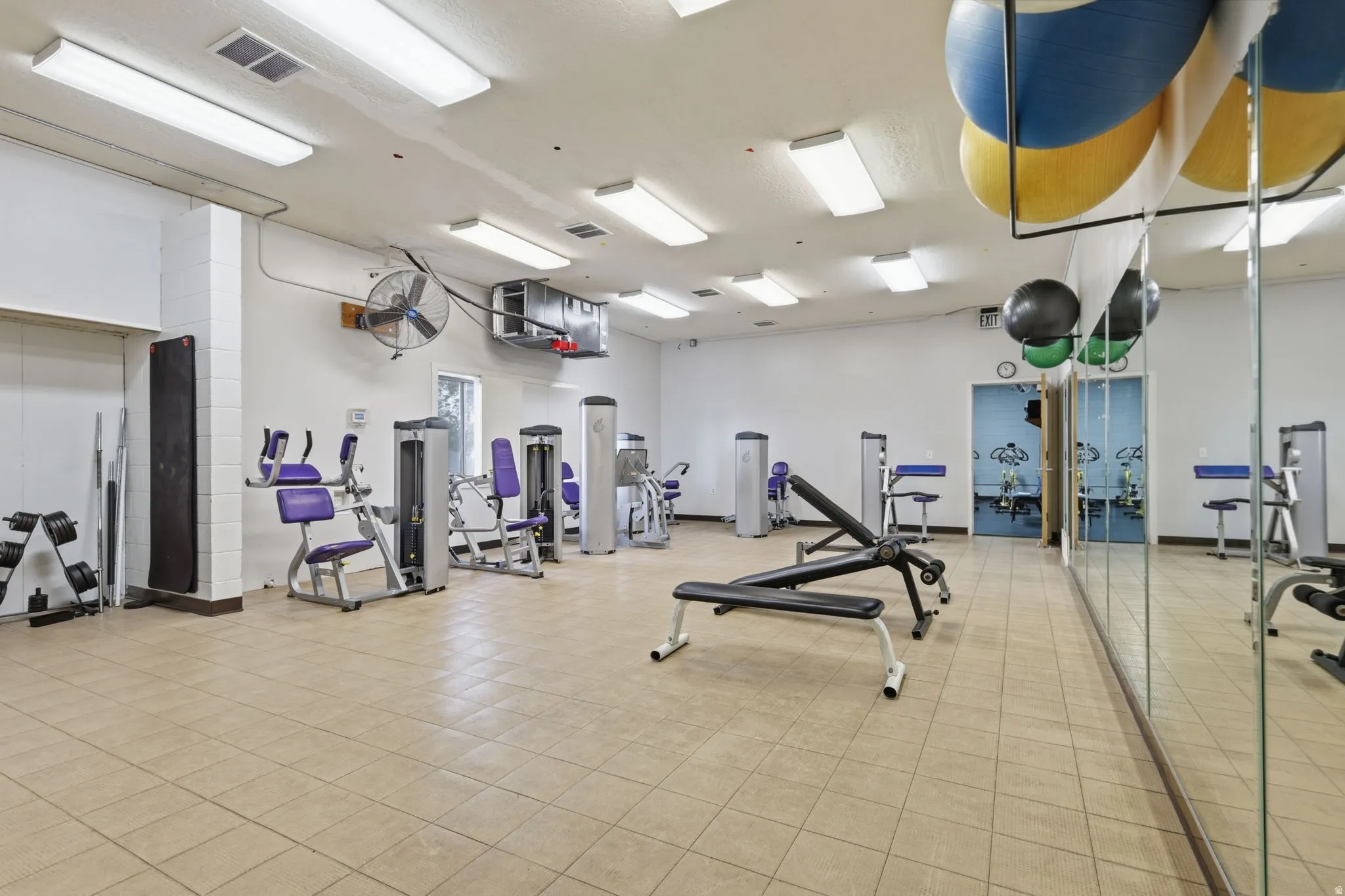 Fitness facility with tiled flooring, mirrored wall, recessed lighting, and various exercise equipment