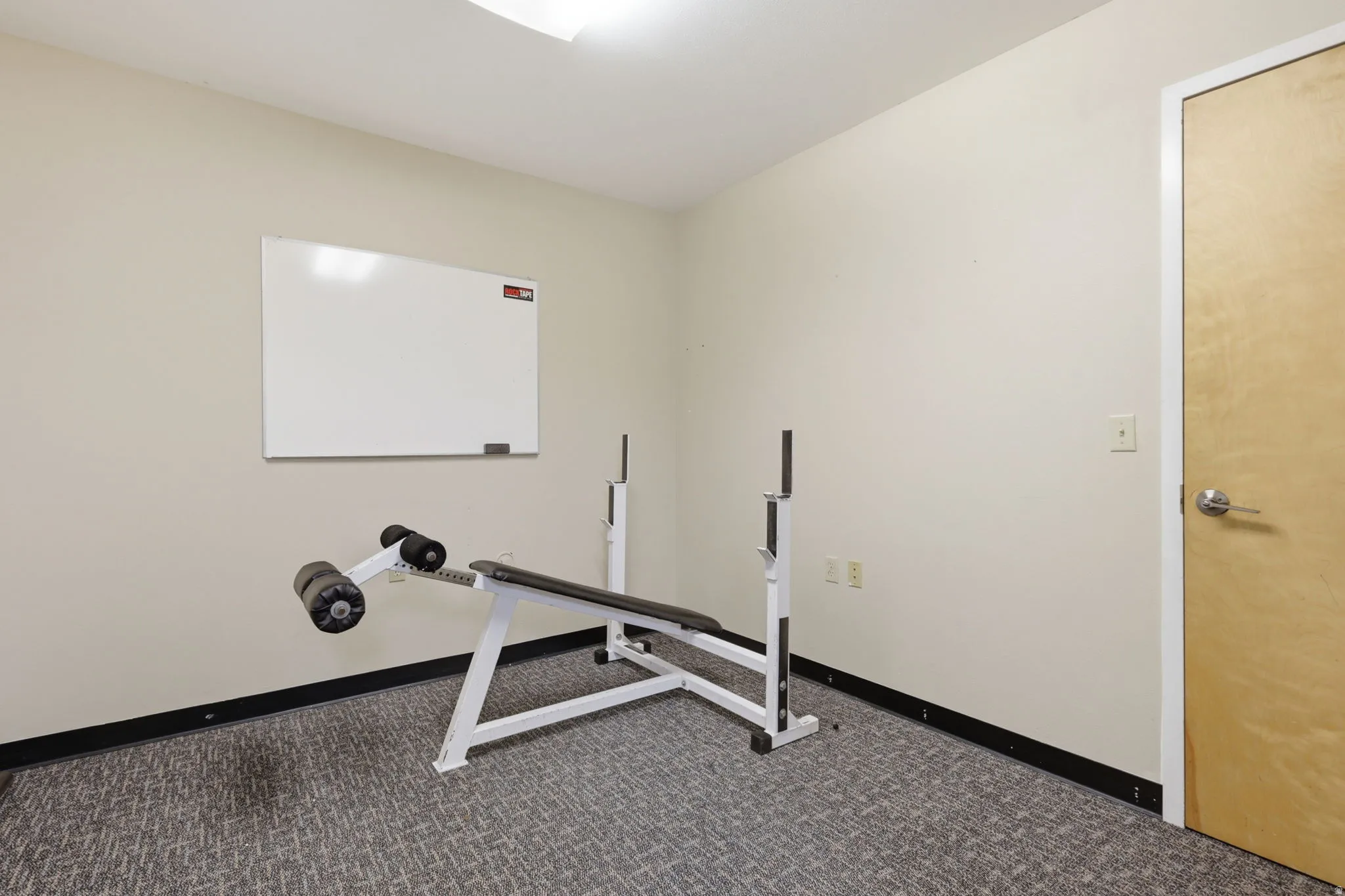 Wall-mounted whiteboard and light wood-finish door with brushed nickel hardware
