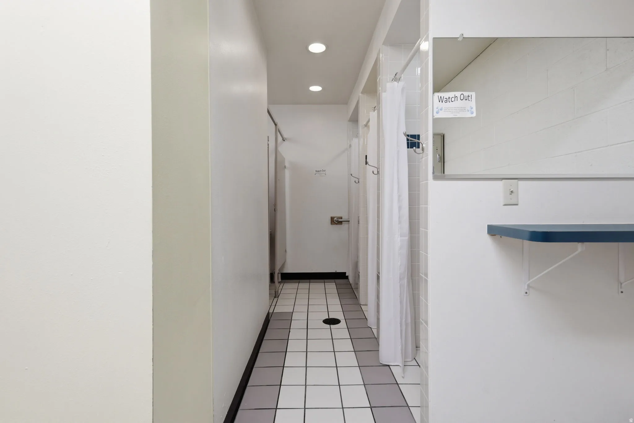 Recessed lighting illuminates the tiled flooring with a grid pattern
