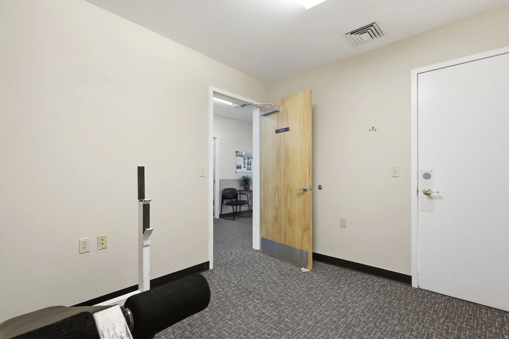 Recessed lighting, wood-finish interior door, and textured carpet flooring