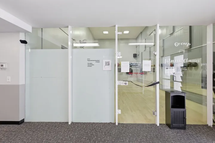 Glass partition walls with frosted privacy panels, clear glass doors, and light wood-finish flooring