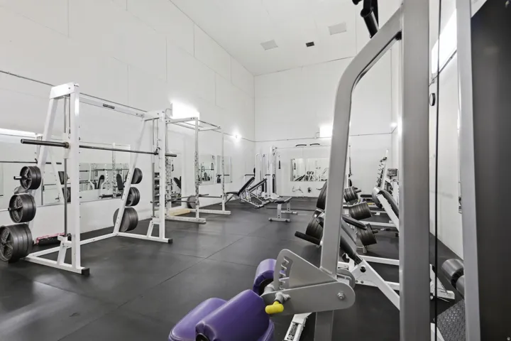 Dedicated fitness space featuring rubberized flooring and multiple mirrored walls