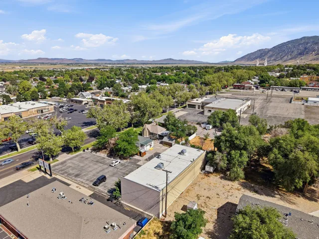 Aerial view showcasing a commercial property with flat roof construction and concrete paving, surrounded by mature landscaping and established trees
