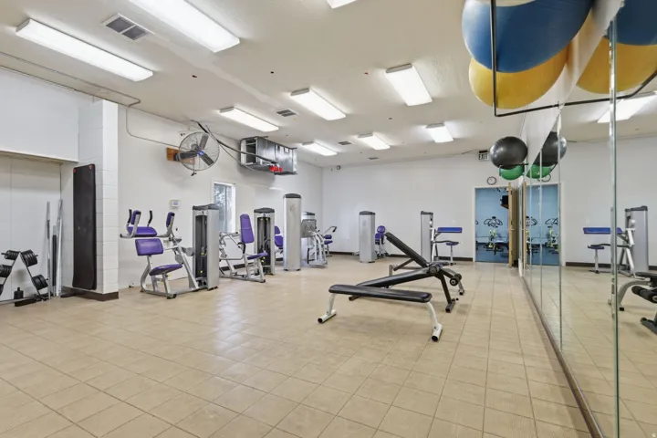 Fitness facility with tiled flooring, mirrored wall, recessed lighting, and various exercise equipment