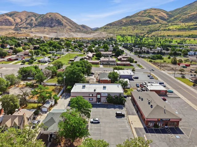 Aerial view showcasing this commercial property positioned along a main thoroughfare, with ample parking facilities and a modern white building structure