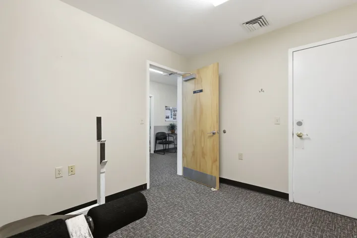 Recessed lighting, wood-finish interior door, and textured carpet flooring