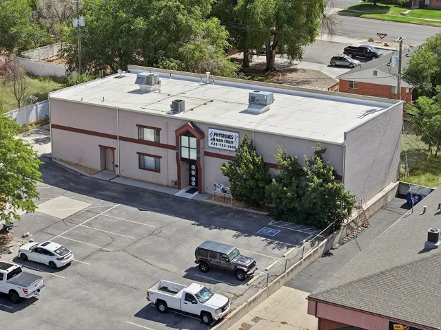 Commercial building with a flat roof, a paved parking area, and mature landscaping