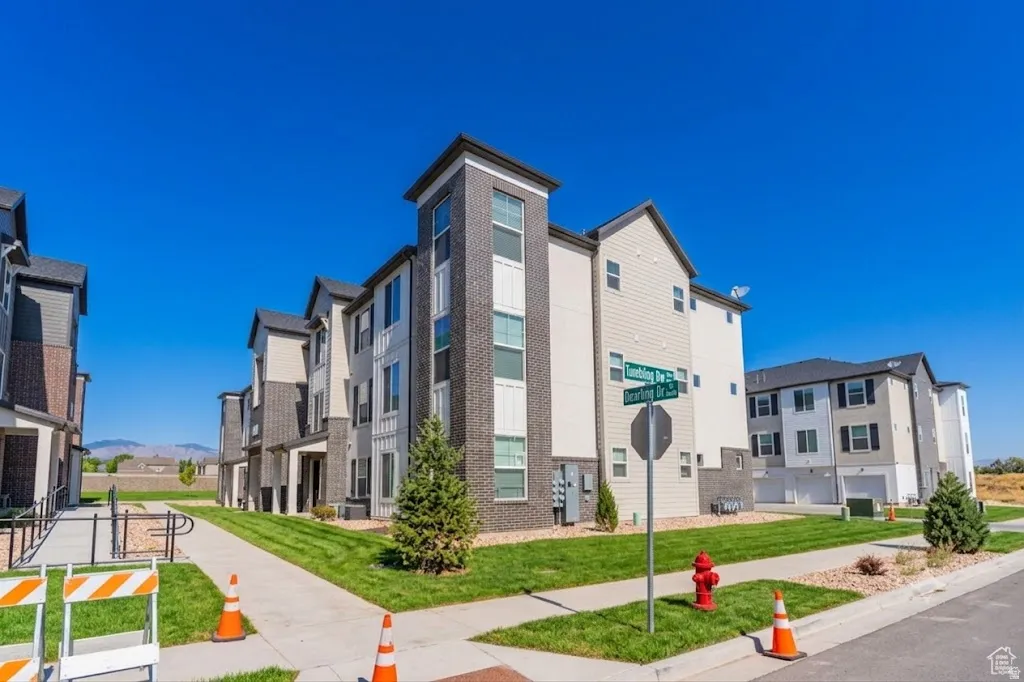 Modern townhome exterior with mixed material siding, dark-framed windows, and an attached garage