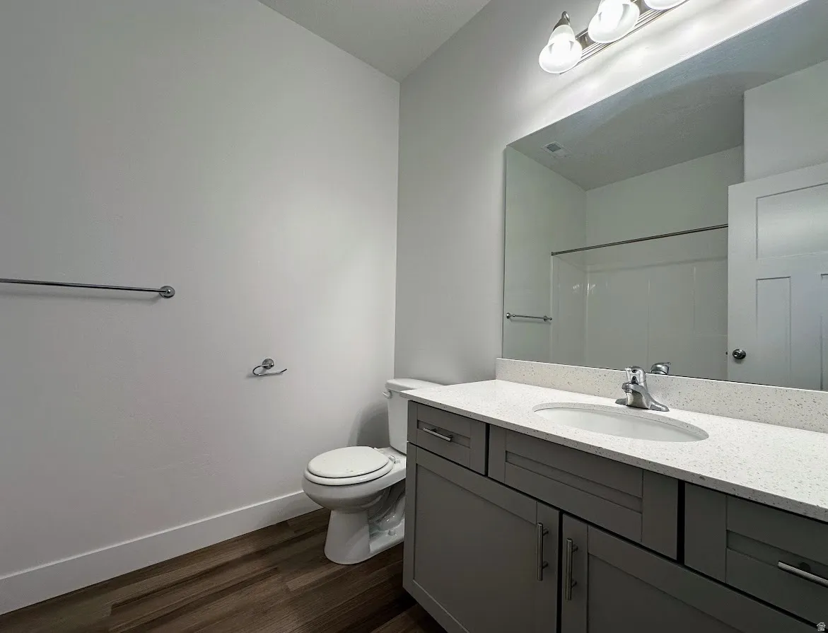 Bathroom with wood-finish flooring, a contemporary vanity with a white countertop, and an integrated sink with a chrome faucet
