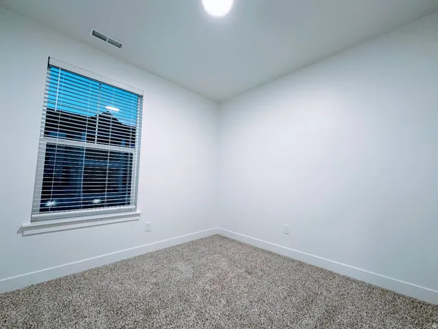 Recessed lighting, neutral-toned carpeting, white walls, and a window with blinds