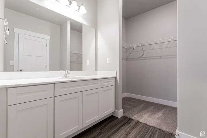 Dual vanity with light gray shaker-style cabinetry, white speckled countertop, and integrated sink