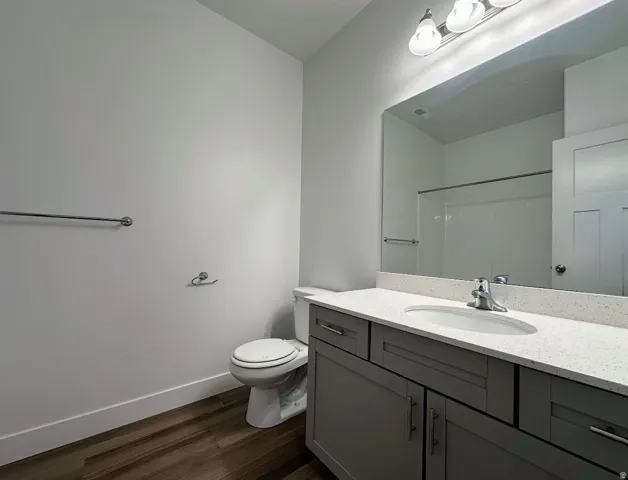 Bathroom with wood-finish flooring, a contemporary vanity with a white countertop, and an integrated sink with a chrome faucet