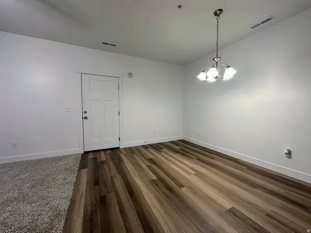 Wood-finish flooring, white walls, and a four-light chandelier