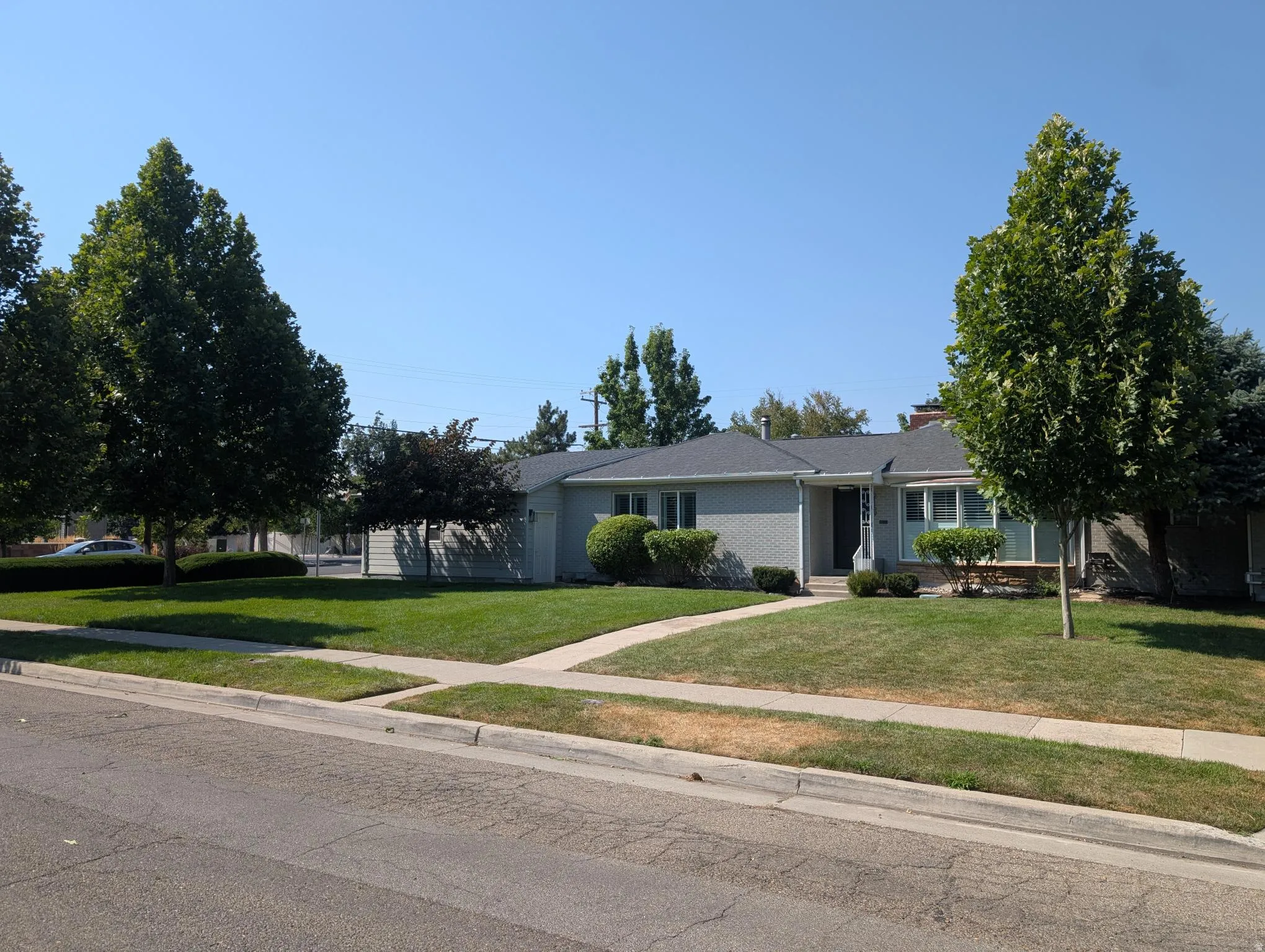 Charming single-story residence with a manicured front lawn, mature landscaping, and established shade trees