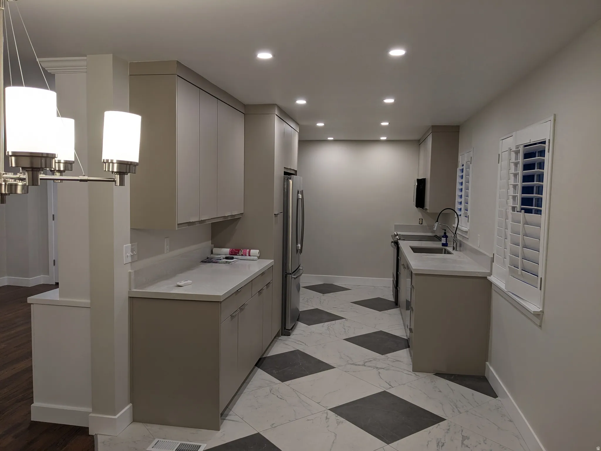 Kitchen featuring recessed lighting, contemporary cabinetry, light-toned countertops, stainless steel appliances, and checkerboard floor tiling