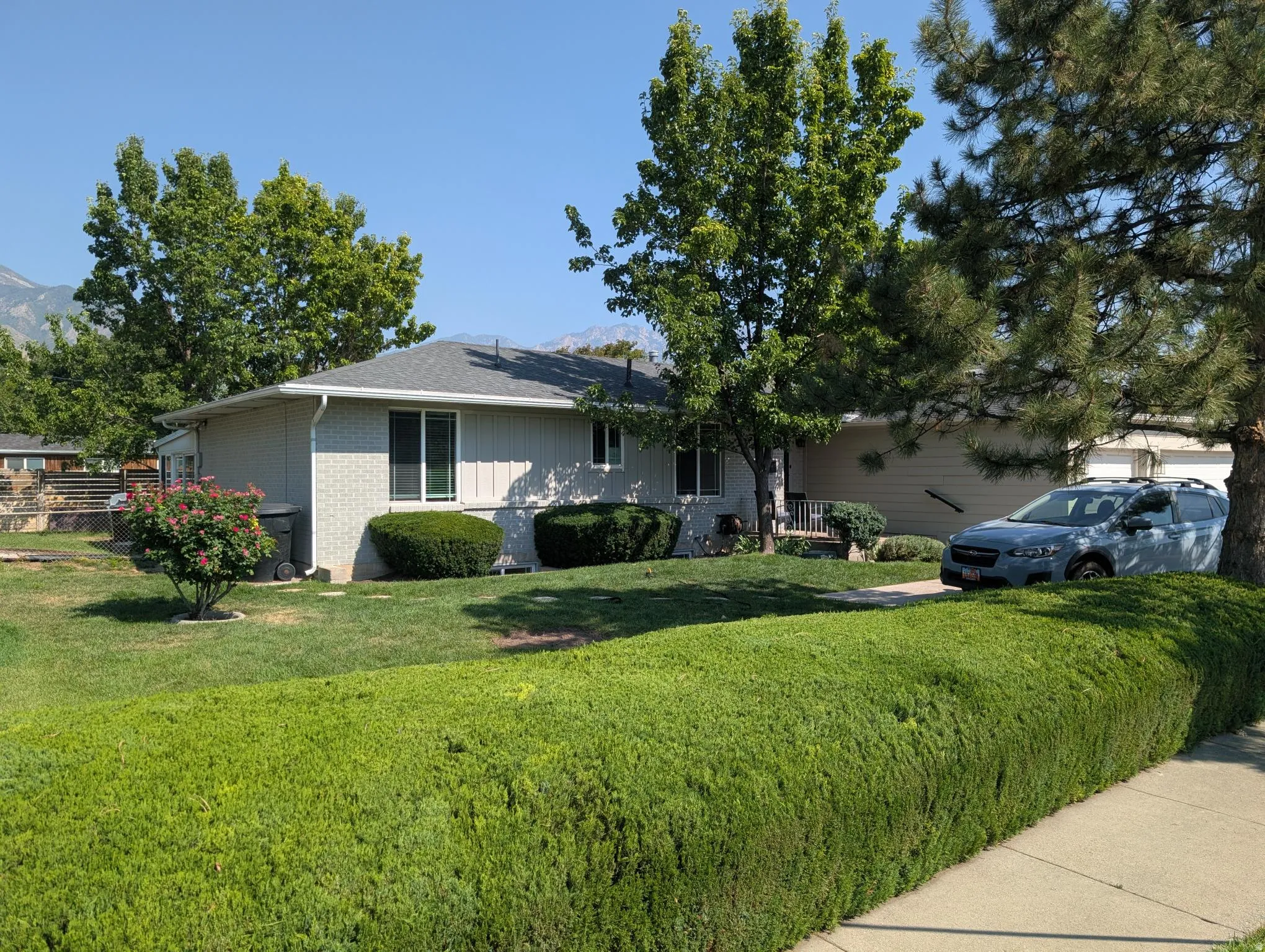 Brick and siding exterior, established landscaping, mature trees, and a concrete driveway