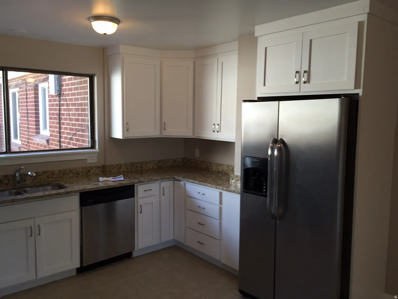 White shaker-style cabinetry, granite-finish countertops, stainless steel appliances, and a double basin sink