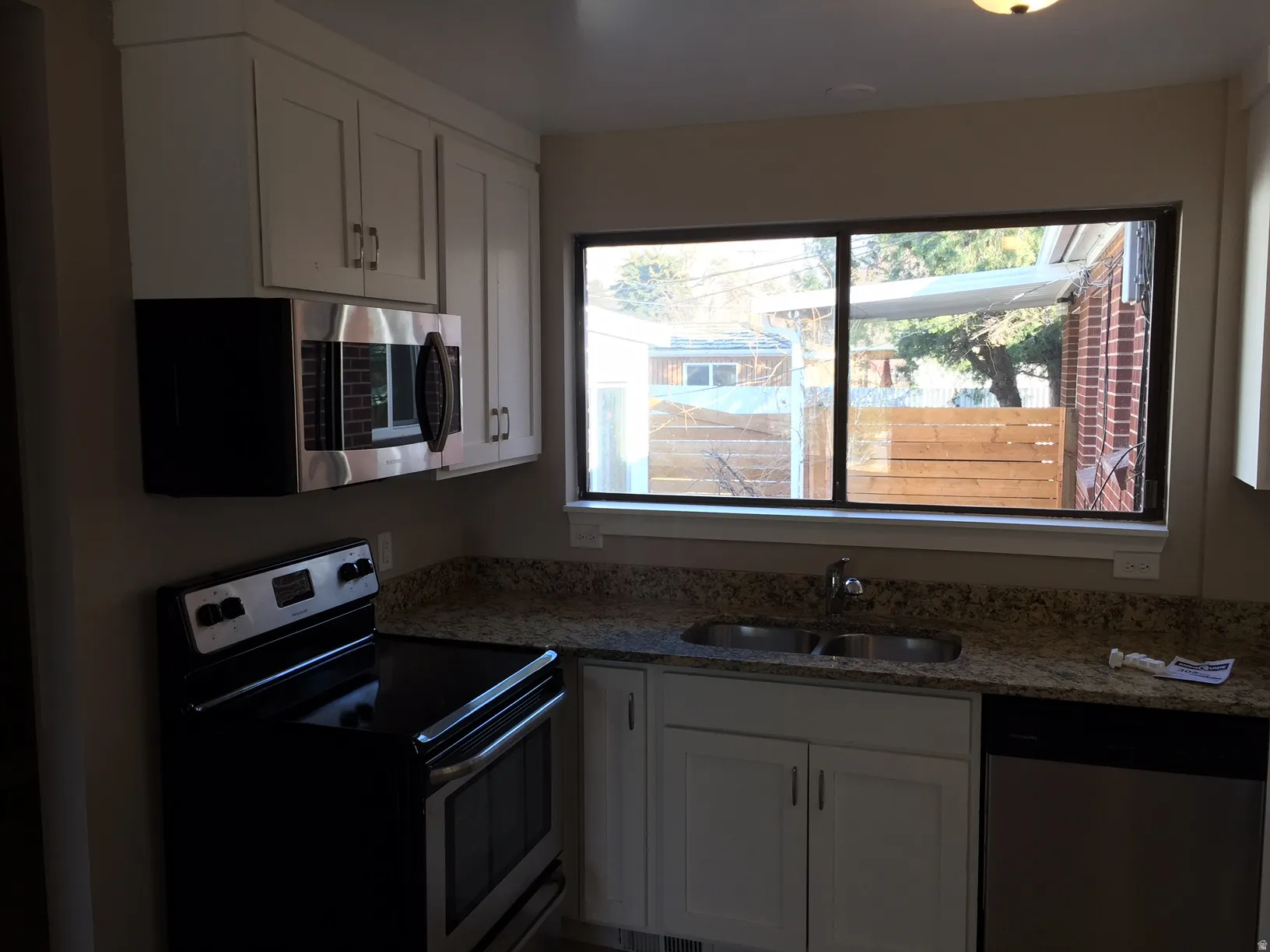 Stainless steel appliances, white cabinetry, granite countertops, and a double basin sink