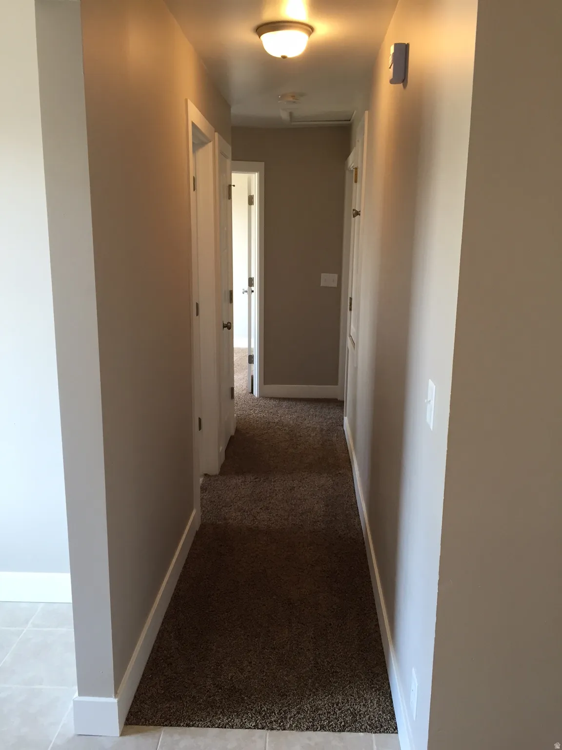 Hallway with neutral wall tones and dark carpeting