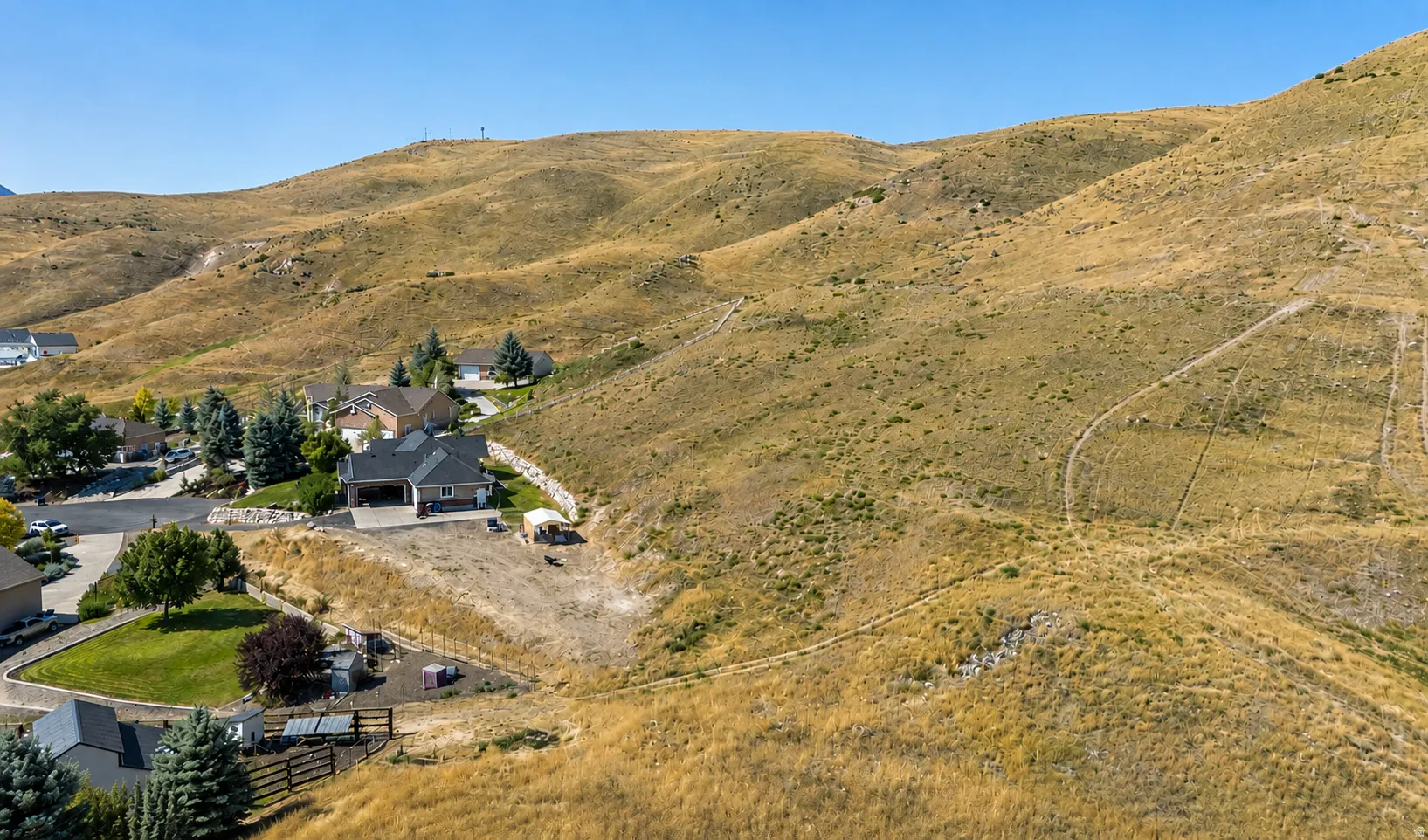 Hillside residence with an attached garage, surrounded by natural terrain and distant mountains