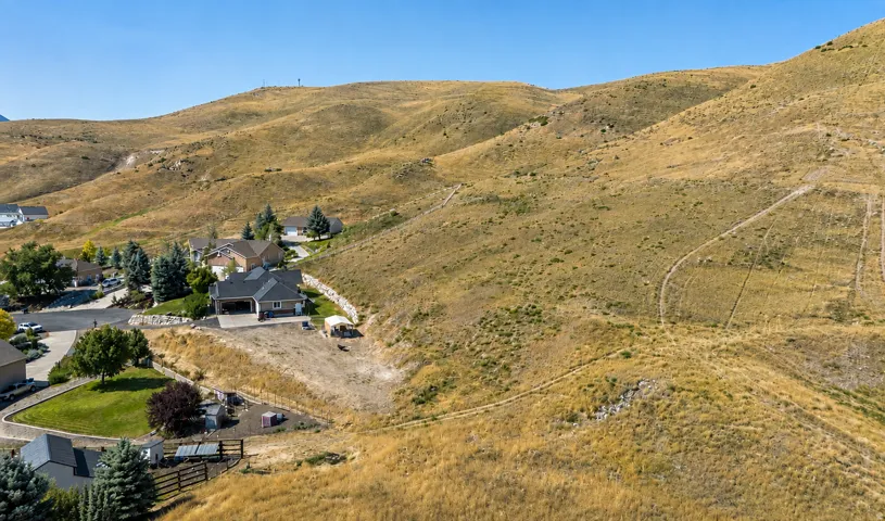 Hillside residence with an attached garage, surrounded by natural terrain and distant mountains