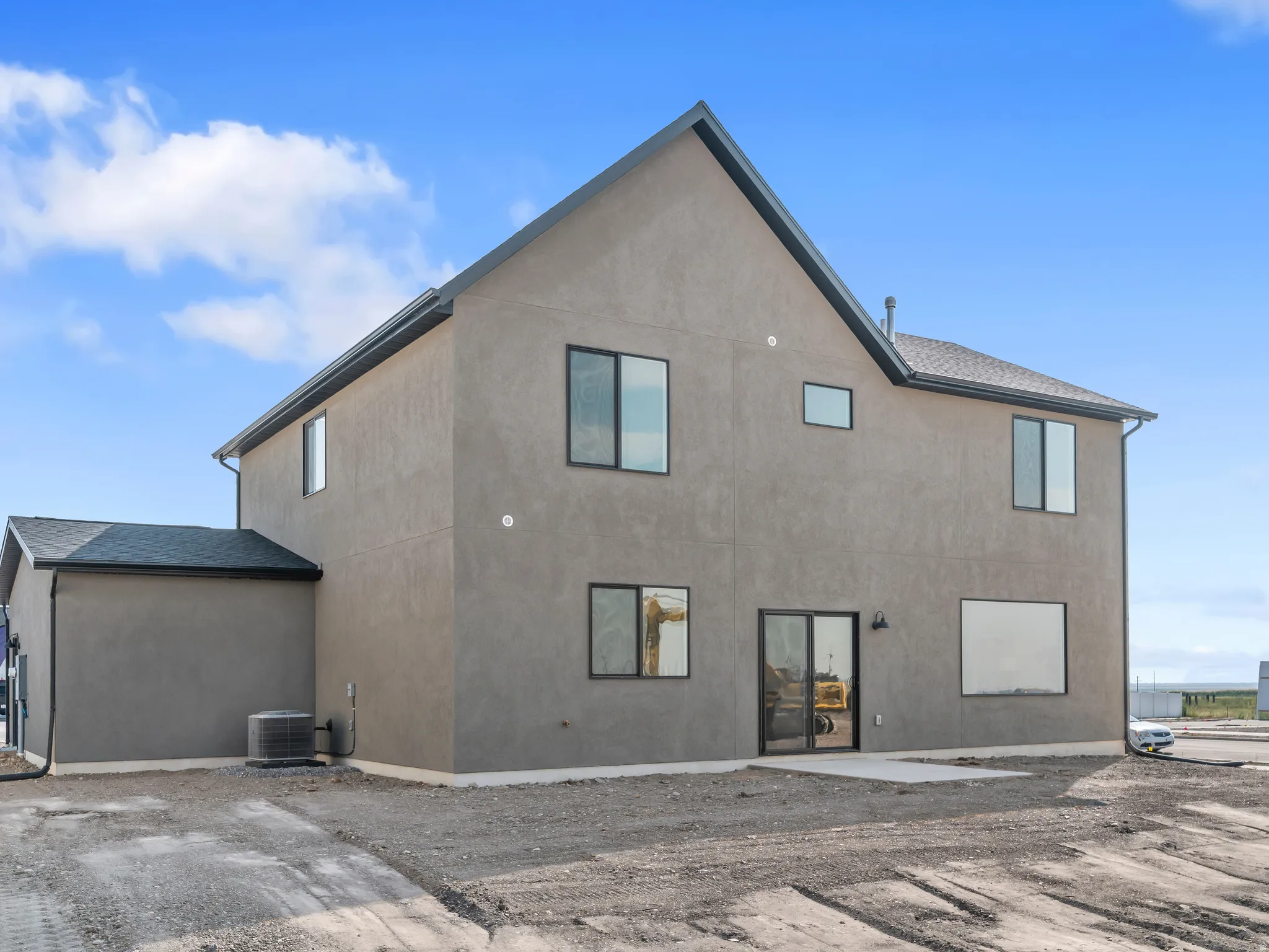 Stucco exterior with a pitched roofline, featuring black-framed windows and a glass sliding door