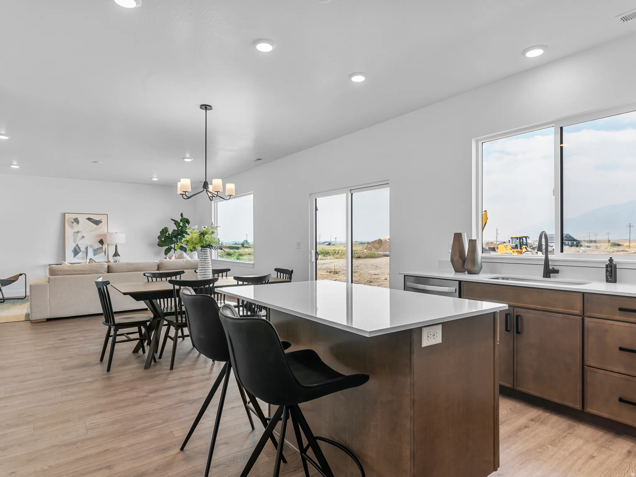 Open-concept living space featuring wood-finish flooring, recessed lighting, and a kitchen island with a white countertop