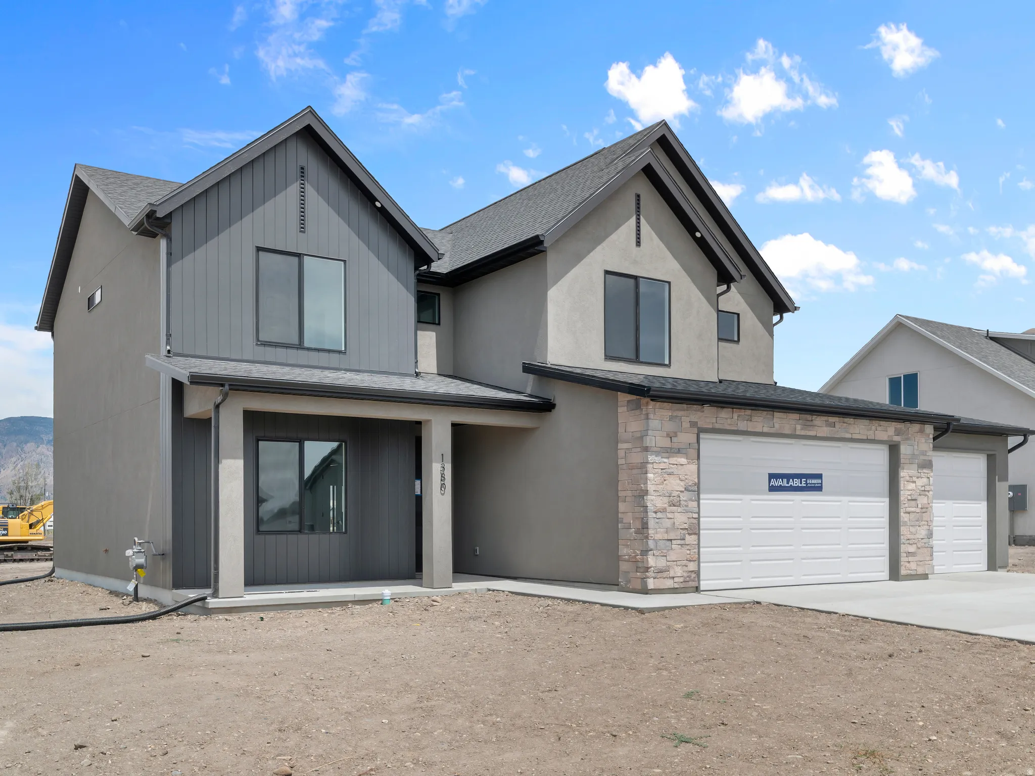 Contemporary exterior with contrasting siding, stone accent facade, a two-car garage, and dark-framed windows