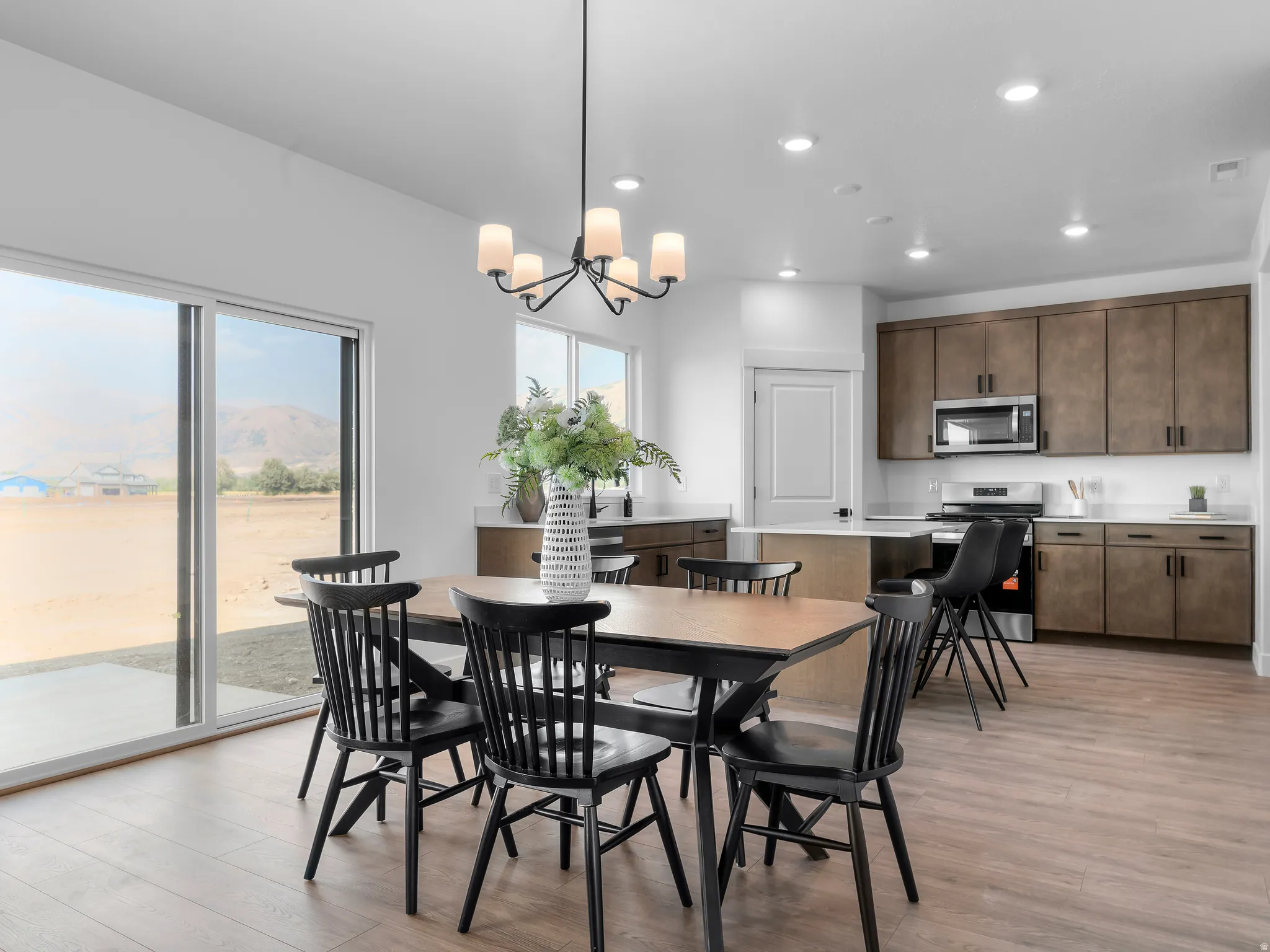 Spacious open-concept area featuring wood-finish flooring, a contemporary chandelier, and recessed lighting