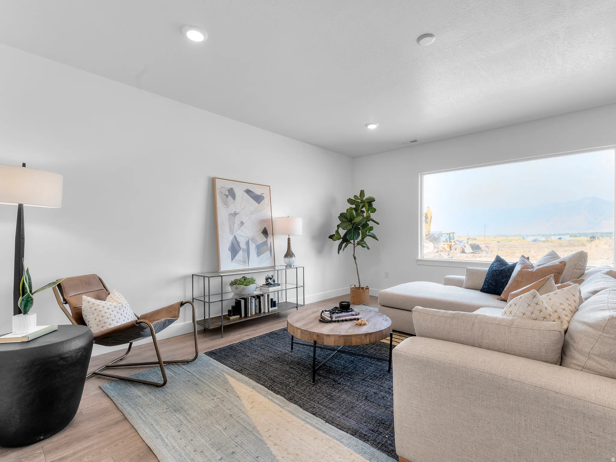 Recessed ceiling lighting, wood-finish flooring, expansive window, white walls, and a metal-frame console table