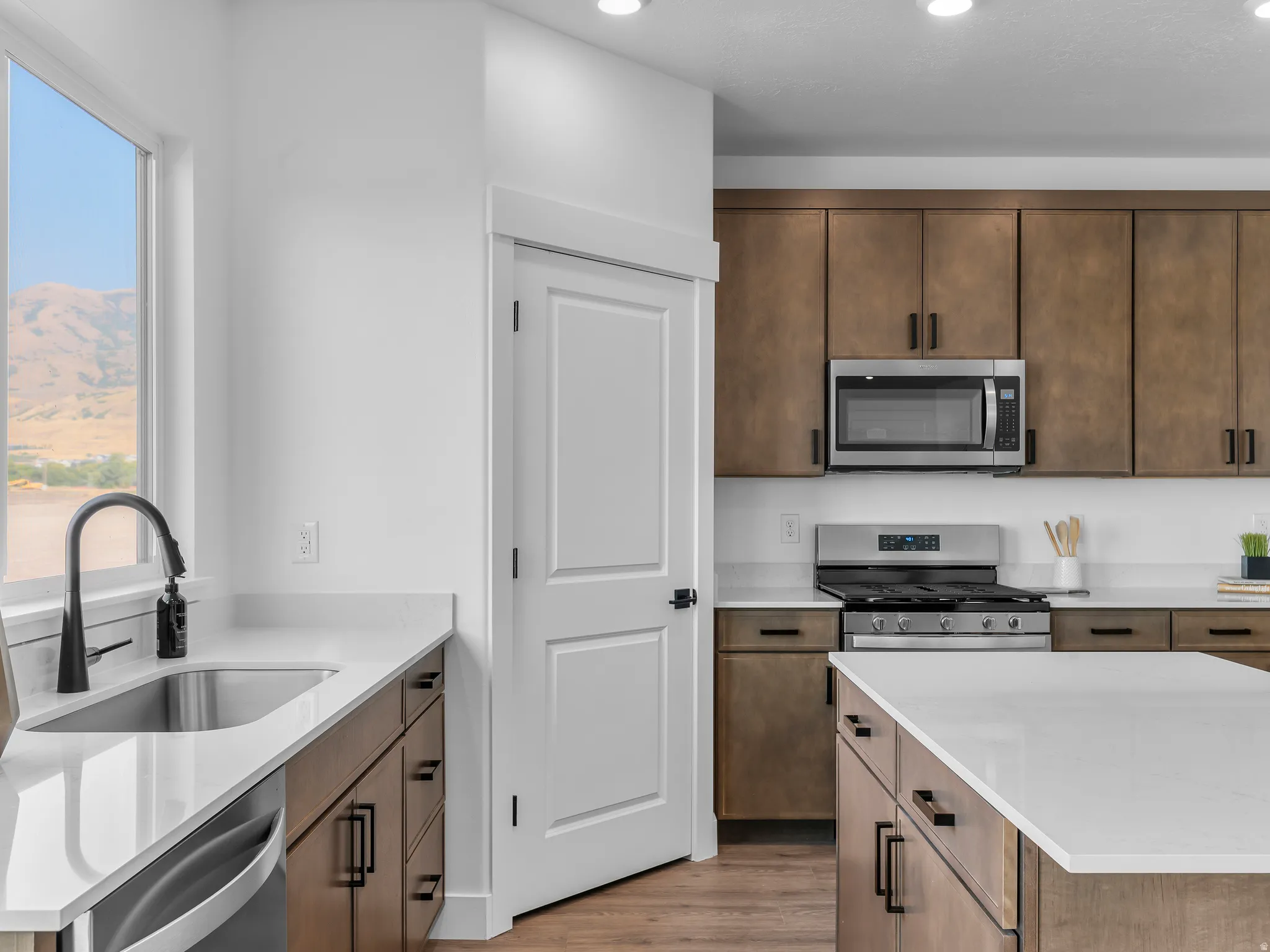 Kitchen featuring wood-finish cabinetry, stainless steel appliances, white countertops, and recessed lighting