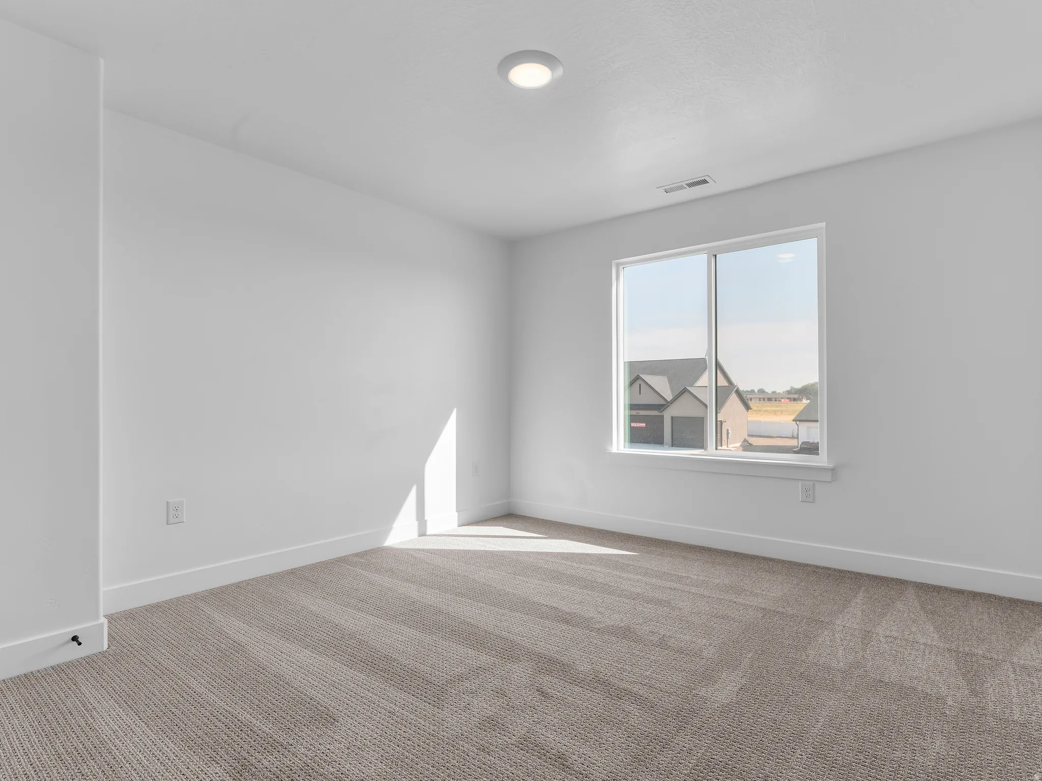 Recessed ceiling lighting, white walls, large window, patterned carpet flooring, and white trim