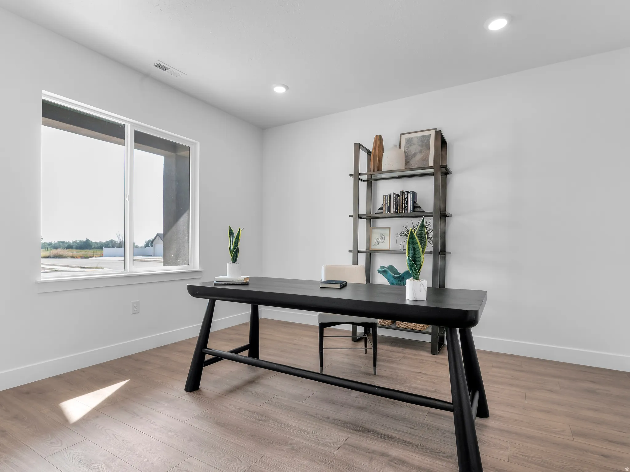 Spacious room with wood-finish flooring, recessed lighting, and a large window