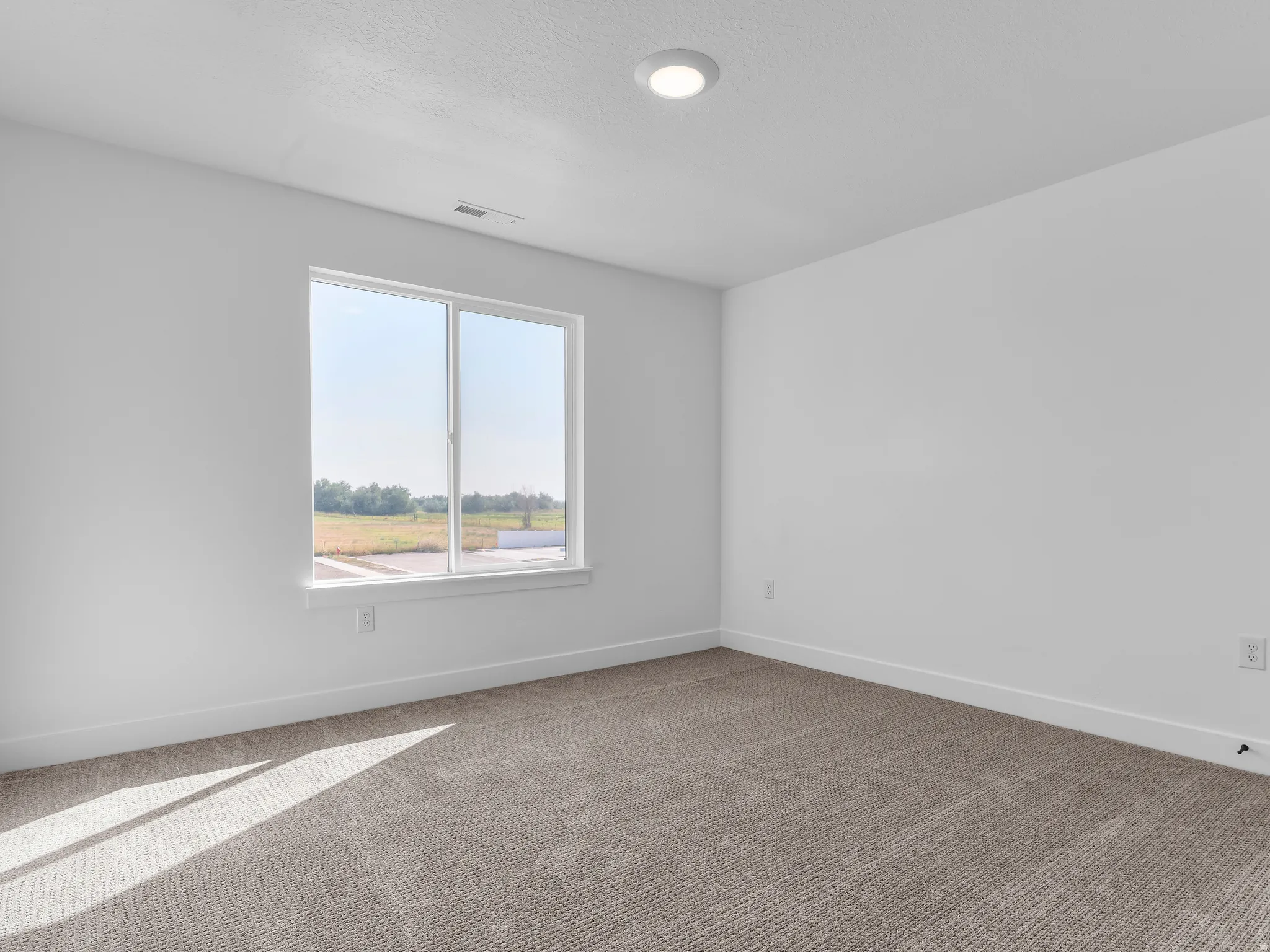 Recessed ceiling light with a large window, neutral carpet, and white walls