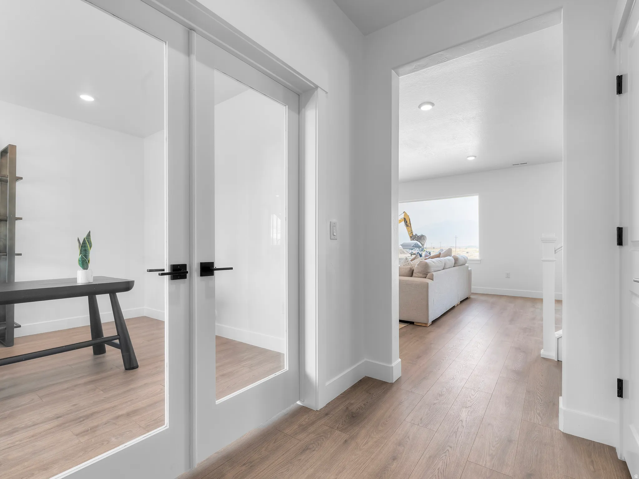 Frosted glass French doors, recessed lighting, wood-finish flooring, and crisp white walls