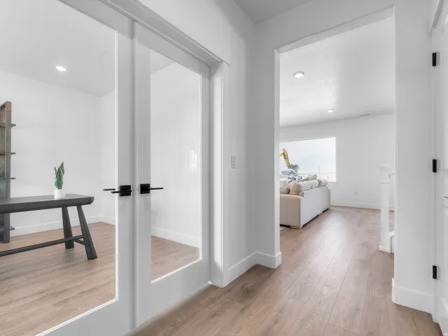 Frosted glass French doors, recessed lighting, wood-finish flooring, and crisp white walls